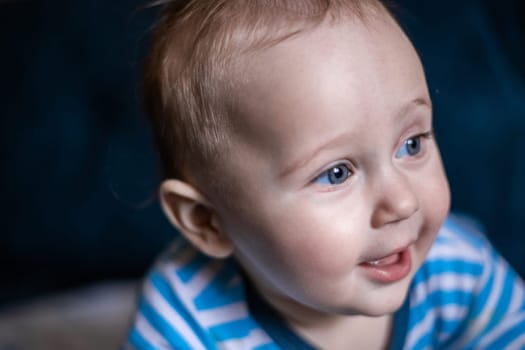 A kid in a striped jumpsuit looks away from the camera and smiles, close-up. . High quality photo