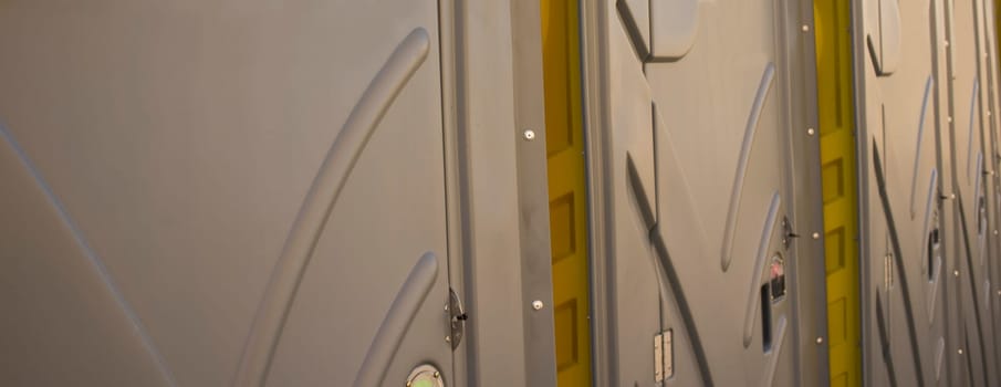 Row of dark grey portable toilets. Outdoors shot