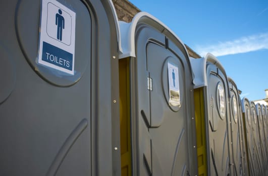 Row of dark grey portable toilets. Outdoors shot