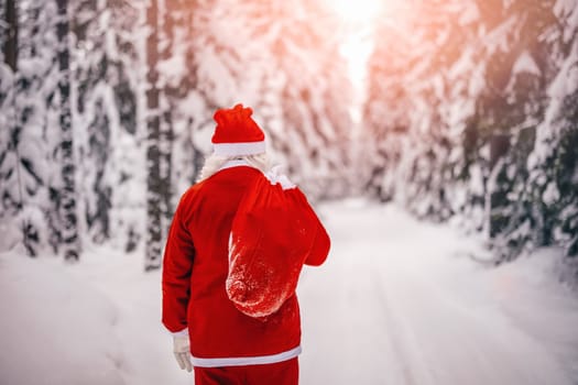 Santa Claus with sack of presents walking in the winter forest. Beautiful view in the snowy natural park.