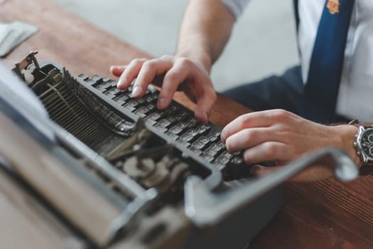 Man working on retro typewriter at desk in parlor room.