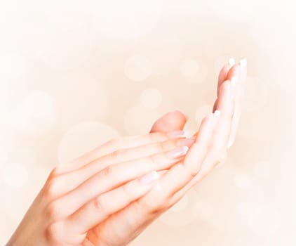 Beautiful female hands with french manicure with bokeh background