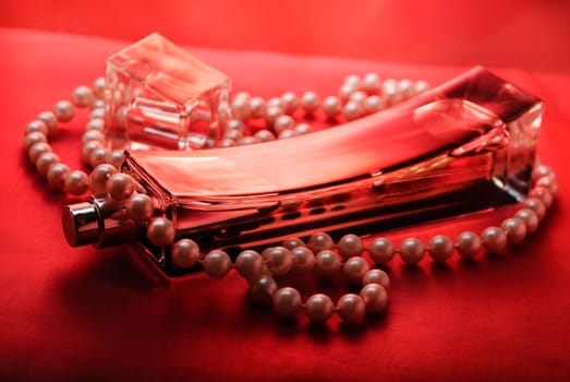 Bottle of perfume and pearls on purple silk