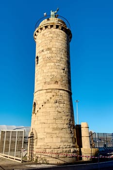 Civitavecchia, Italy - December 19, 2024: Historic stone lighthouse with a statue on top under a vivid blue sky. Concept: architecture, heritage, travel, and landmarks.