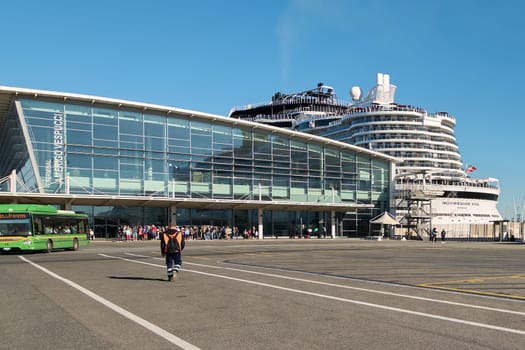 Civitavecchia, Italy - December 19, 2024: Modern Amerigo Vespucci cruise terminal with a docked cruise ship and a green bus on a sunny day. Concept: tourism, travel, port.