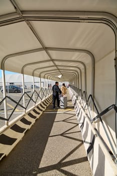 Civitavecchia, Italy - December 19, 2024: Covered walkway at the port with travelers carrying luggage, leading to a parking area. Concept: mobility, tourism, infrastructure.