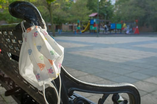 Playground bench with two face mask hooked. Covid-19 easing lockdown restrictions