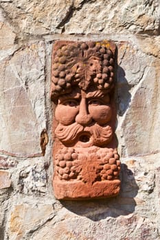 old medieval stone wall with face of baccus, the god of winery