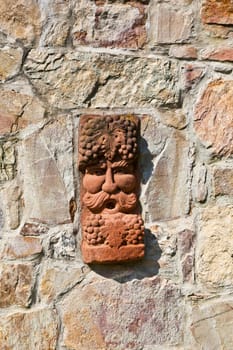 old medieval stone wall with face of baccus, the god of winery