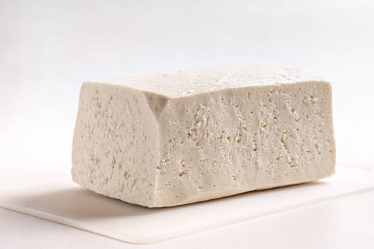 A white cheese on a white surface and white background