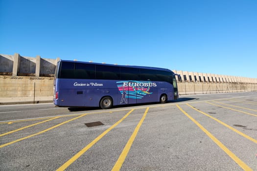 Civitavecchia, Italy - December 19, 2024: A blue tour bus marked Crociere in Pullman and EUROBUS is parked in a lot with yellow lines, showcasing transportation and tourism.