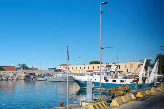 Civitavecchia, Italy - December 19, 2024: Ships, including fishing boats and coast guard vessels, dock in the port of Civitavecchia under a blue sky, highlighting maritime activities and port life.