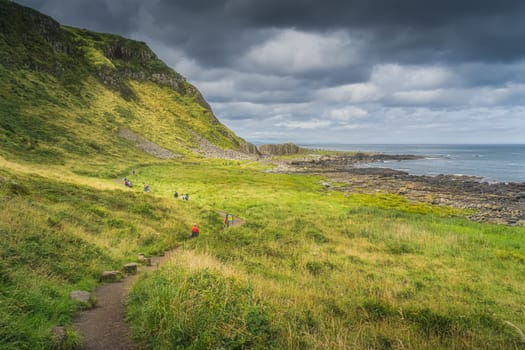 Tourists on path to main hexagonal rock formation, basalt columns in Giants Causeway, Wild Atlantic Way and UNESCO world heritage, Northern Ireland