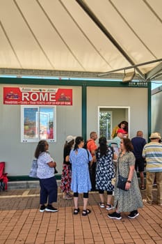 Civitavecchia, Italy - December 19, 2024: Tourists gather at a ticket booth in Civitavecchia to buy tickets for Rome tours, with services like transfers, train tickets, and hop-on hop-off tours