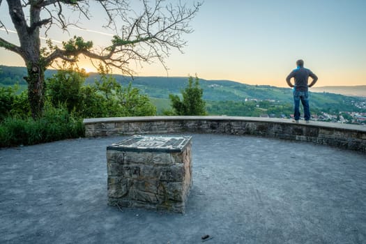 Man is standing at a wall and is looking at the sunrise