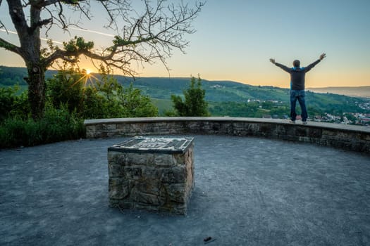 Man with arms in the air enjoy the sunrise with rays