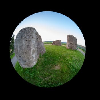 Stone rocke on green meadow with blue sky fish-eye distortion