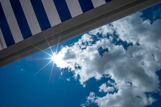 Blue awning with blue sky and clouds and star of the sun concept