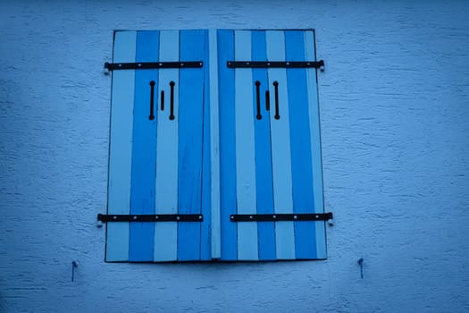 Blue window shutter on blue wall exterior