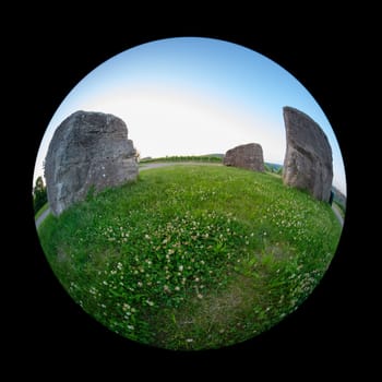 Three rocks on green meadow with fish-eye distortion