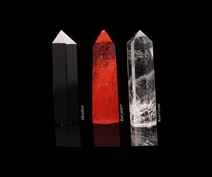 Set of crystals of semi-precious stones: obsidian, rhinestone, red jasper with natural reflection isolated on black glossy background