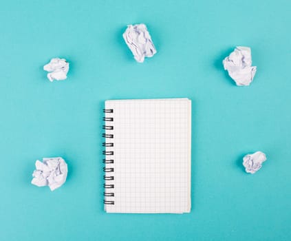 Empty notebook with paper crumbles around, blue colored background, copy space, new idea, brainstorming