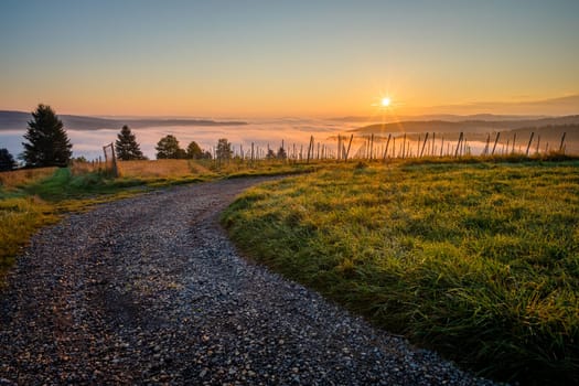 Sunstar of sunrise fiield road and meadow with mist in valley