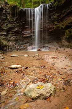 Waterfall cascade is flowing over rock in german forest