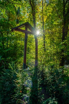 Memorial cross in forest sunlight scenery