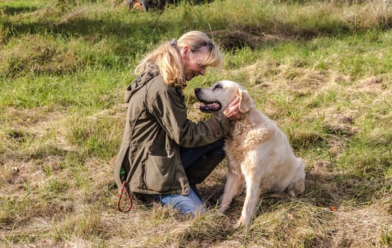 Dog owner kneels in front of her dog and is happy