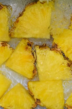 Close up view of the yellow pineapple slices in lemonade background. Texture of cooling sweet summer's drink with macro bubbles on the white background. Flat design. Vertical image.