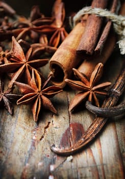 Anise seed, cinnamon and vanilla on grunge wooden plank