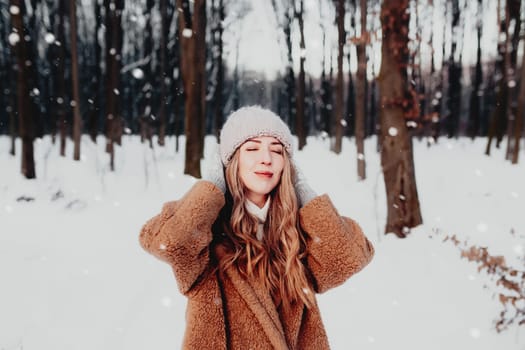 Photo of young beautiful woman in fur coat standing on the white snow in winter forest. Girl is smiling and happy with closed eyes. Female has winter vacation, happily waiting for Christmas holidays