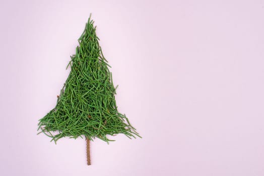 Christmas tree made from fir needles, pink colored paper, copy space, textured background, minimalism