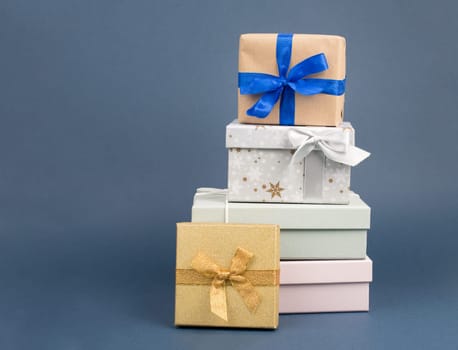 Gift boxes in different sizes and colors in front of a dark blue background, copy space, christmas, birthday, holiday presents
