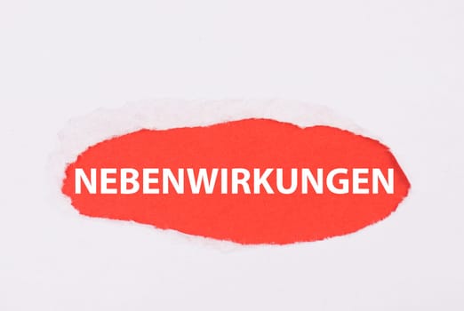 The word side effects is standing on a red colored background, german language, torn paper, covid-19 vaccination