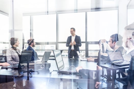Successful team leader and business owner leading informal in-house business meeting. Businessman working on laptop in foreground. Business and entrepreneurship concept.