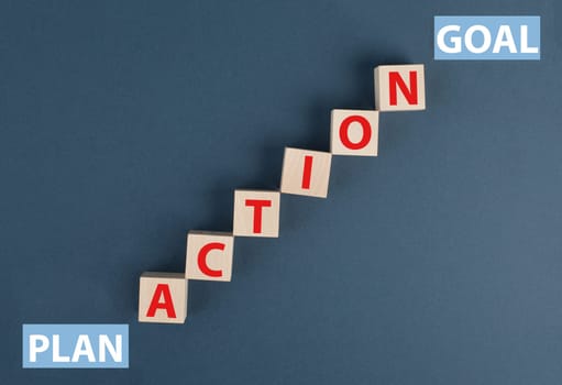 The word action is standing on wooden cubes, plan at the start, goal at the top of the stairs, words, blue background, symbol business concept