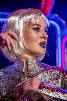 close-up of blonde girl as cyber robot. cyber girl in shining silver armor in neon. blonde with fantastic makeup and image in dark key and colored light. fashion model posing in cyber space.