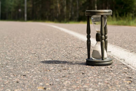 Time concept alarm hourglass on the asphalt road
