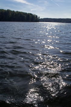 Sunlight twinkling of river water with small waves. Calm summer evening. Vertical image