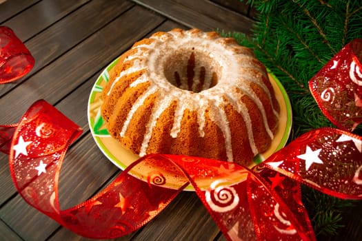 Traditional homemade Christmas cake holiday dessert in Christmas tree decorations frame on dark vintage wooden table background. Rustic style.