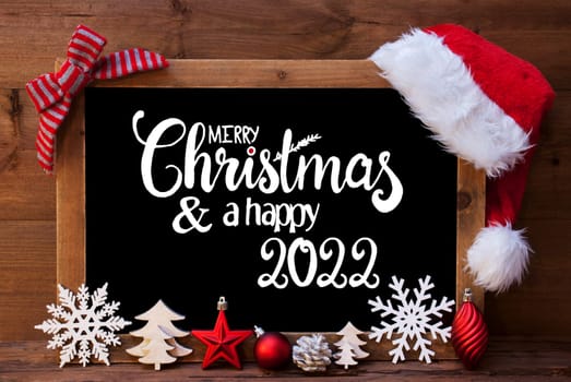 Chalkboard With English Calligraphy Merry Christmas And A Happy 2022. Christmas Decoration Like Tree, Ball, Snowflake And Santa Hat. Wooden Background