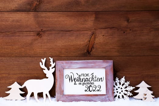 Vintage Frame With German Calligraphy Frohe Weihnachten Und Ein Glueckliches 2022 Means Merry Christmas And A Happy 2022. Christmas Decoration Like Deer And Tree. Wooden Background With Snow