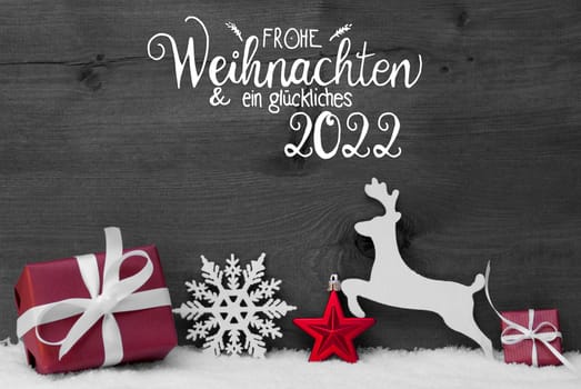 German Calligraphy Frohe Weihnachten Und Ein Glueckliches 2022 Mean Merry Christmas And Happy 2022. Red Christmas Ornament Like Present, Snowflake, Ball And Deer. Gray Wooden Background With Snow