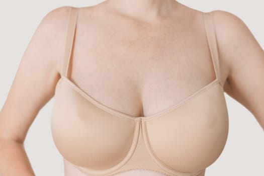 Slim young woman with big boobs wearing underwired bra, Flesh-colored brafitting and underwear concept.