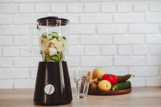 Stationary blender with ingredients for healthy smoothie on table in kitchen.