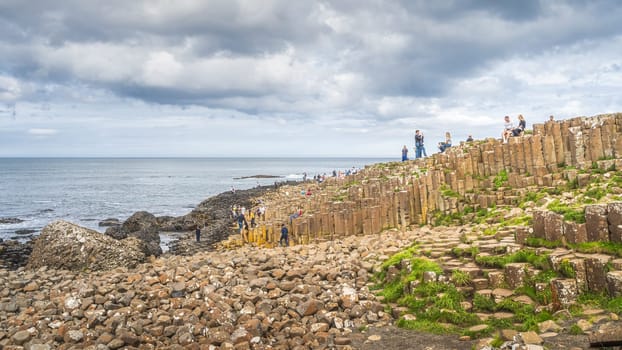 Bushmills, Northern Ireland, Aug 2019 Tourists photographing hexagonal rock formation in Giants Causeway, Wild Atlantic Way and UNESCO world heritage