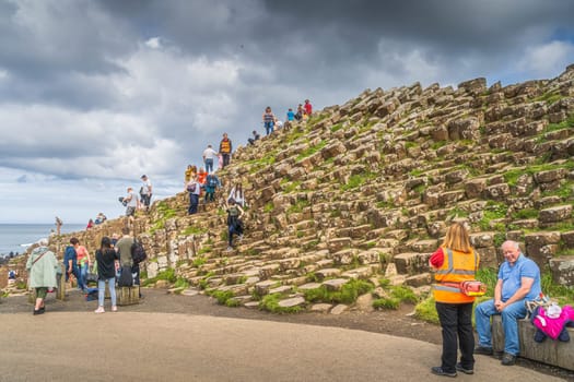 Bushmills, Northern Ireland, Aug 2019 Tourists admiring hexagonal rock formation in Giants Causeway, Wild Atlantic Way and UNESCO world heritage