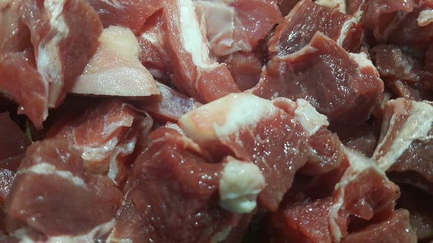 Close up view of fresh finely chopped meat cubes. Red meat small steaks with whitish meat fat.
